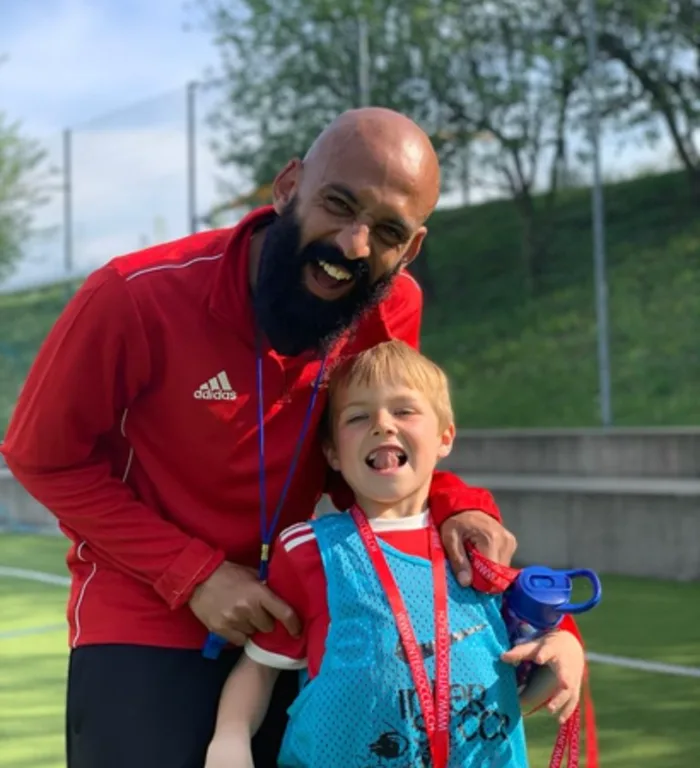 Un entraîneur InterSoccer et un enfant qui rient sur le terrain