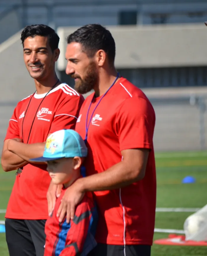 Deux entraîneurs InterSoccer avec un jeune joueur à l'entraînement